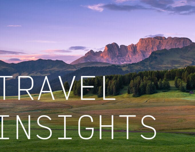 A landscape of rocky plateaus during a purple sunset with the caption "Travel Insights".