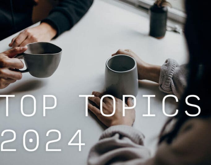 Two people's hands holding coffee mugs on top of a table.