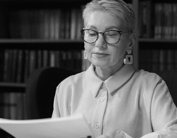 An older women with glasses reading a piece of paper.