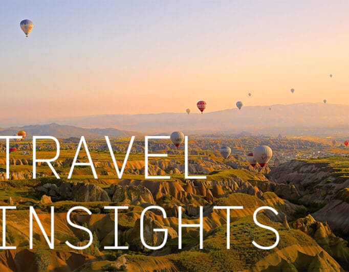 Hot air balloons flying over rolling hills with the caption "Travel Insights".