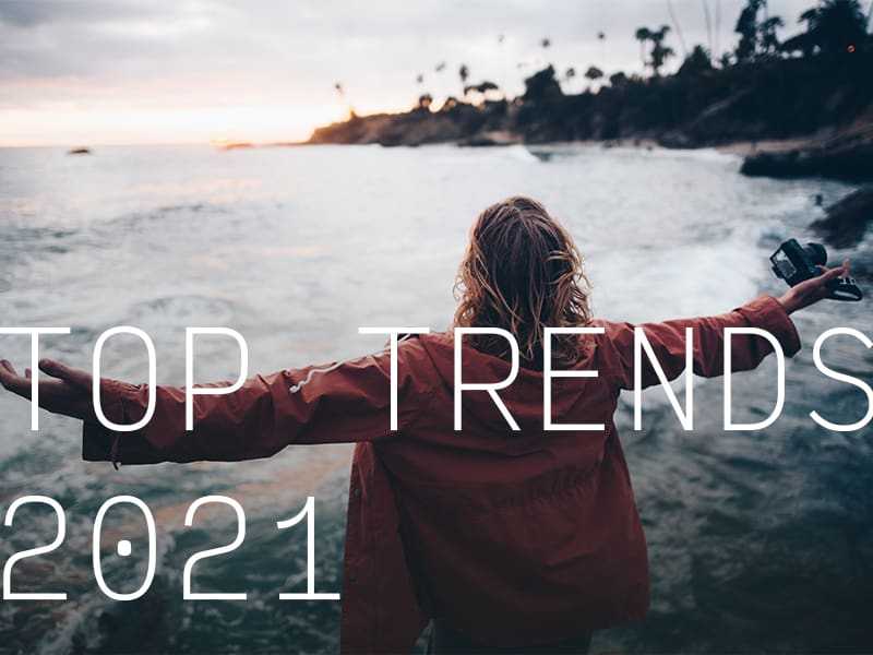 A person on a lake shore with their arms outstretched with the caption "Top Trends 2021".
